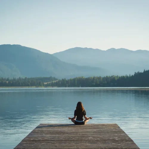 Meditazione su un pontile davanti a un lago di montagna